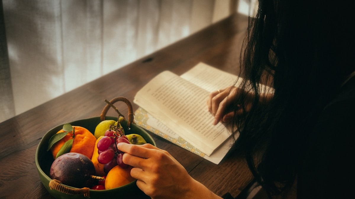 Person reading by a bowl of fruit
